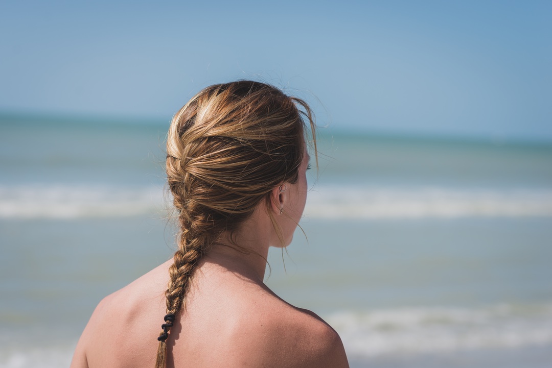 mujer con trenza mirando al mar